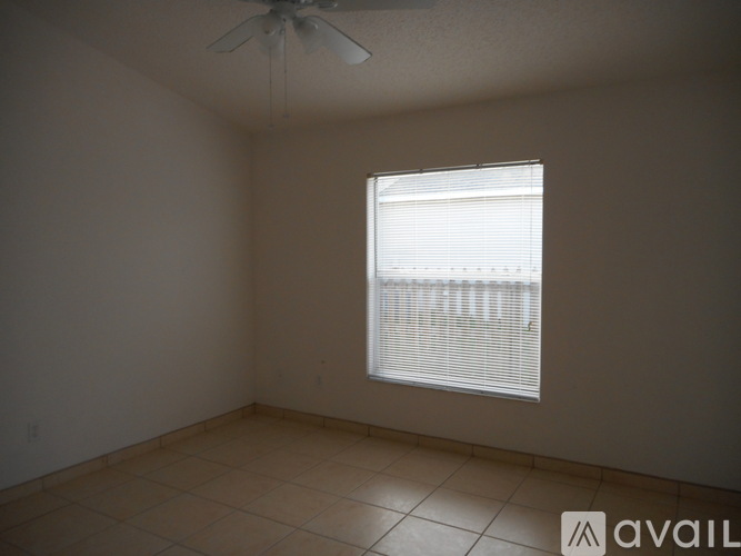 A room with a ceiling fan and a window with blinds.