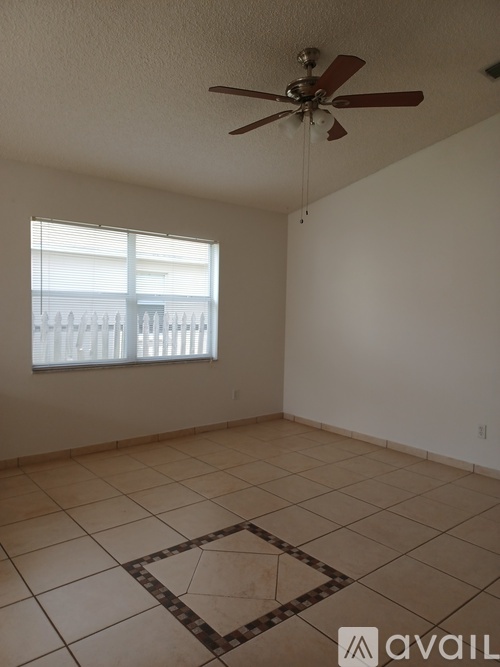 A room with a ceiling fan and a window with blinds.