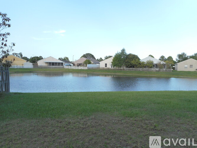 A body of water in front of a house and trees.