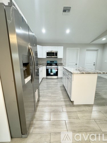 A kitchen with a stainless steel refrigerator and a marble countertop.