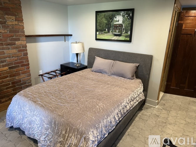A bedroom with a bed, lamp, and a picture on the wall.