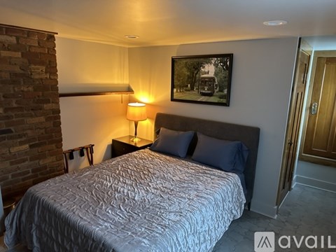 A bedroom with a large bed and a picture on the wall.