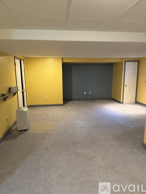 A spacious room with a carpeted floor and a white heater on the left side.