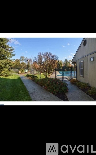 A pathway leads to a building with a pool in the background.