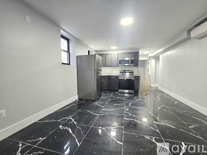 A kitchen with a black marble floor and a stainless steel refrigerator.