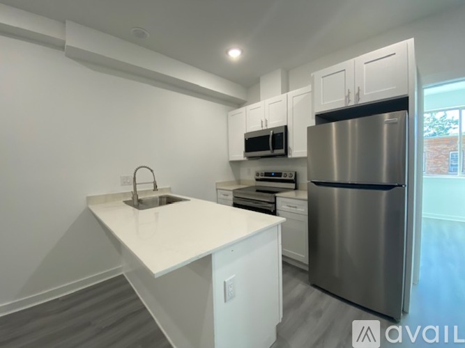 A kitchen with white cabinets and a stainless steel refrigerator.