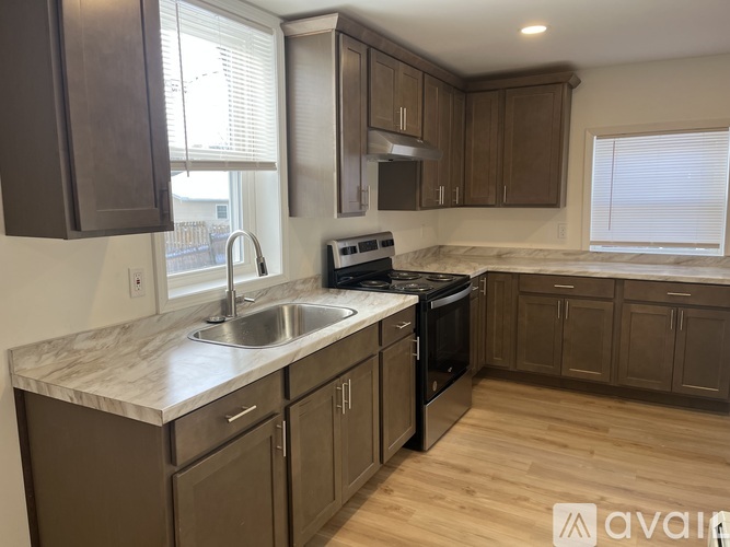 A kitchen with brown cabinets and a marble countertop.