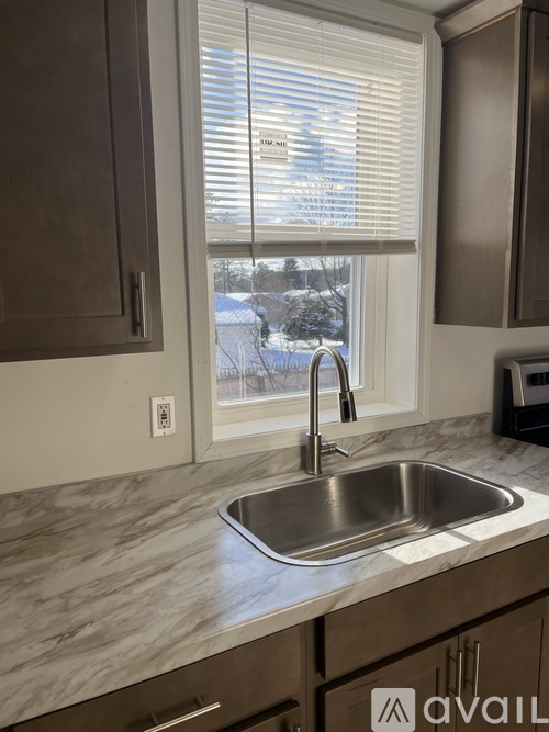A kitchen with a marble countertop and a stainless steel sink.