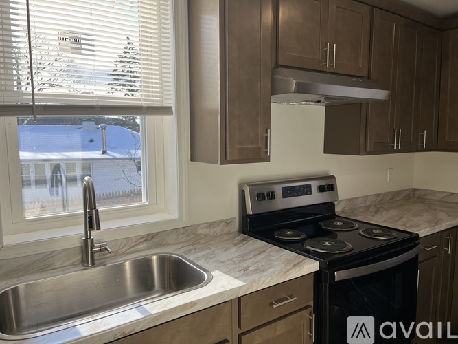 A kitchen with a stove, sink, and cabinets.