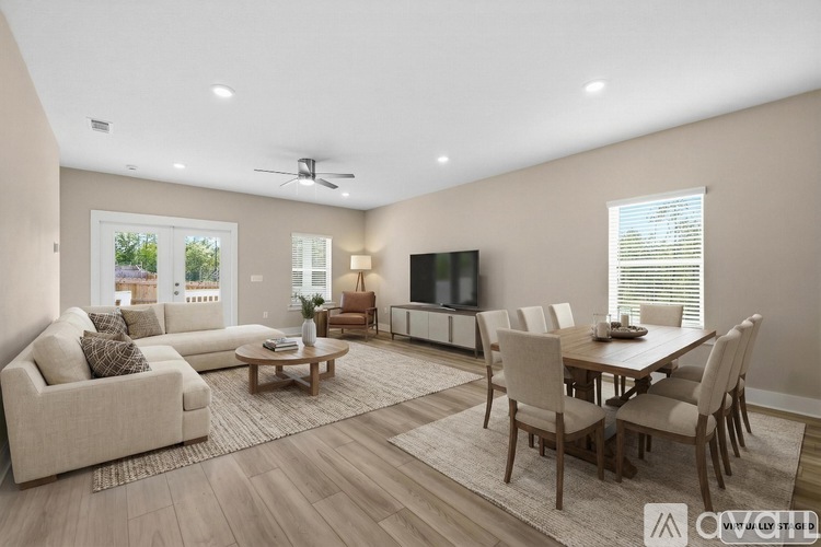 A well-lit living room with a couch, chairs, and a television.