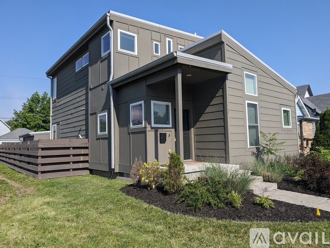 A modern house with a grey exterior and a large front yard.