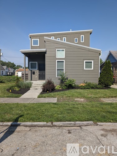 A modern house with a grey exterior and a small front yard.