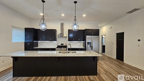 A modern kitchen with black cabinets and a center island.