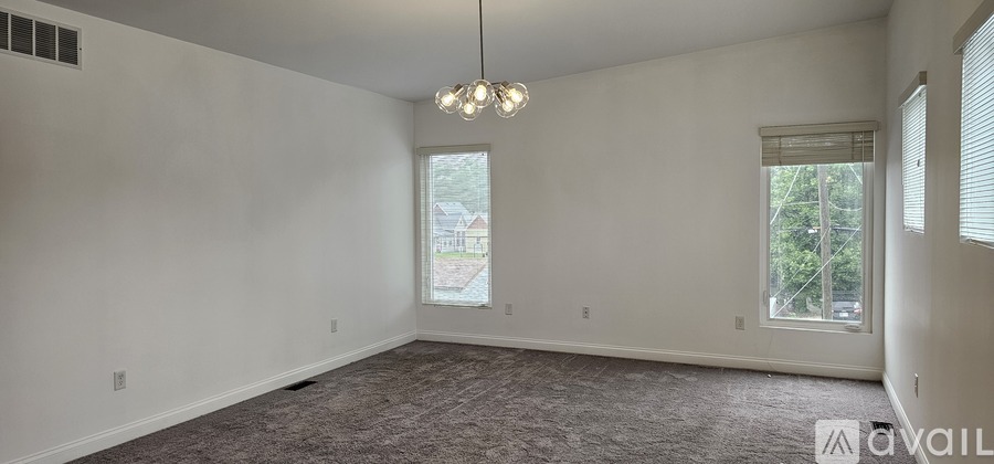 A spacious room with a carpeted floor and a chandelier hanging from the ceiling.