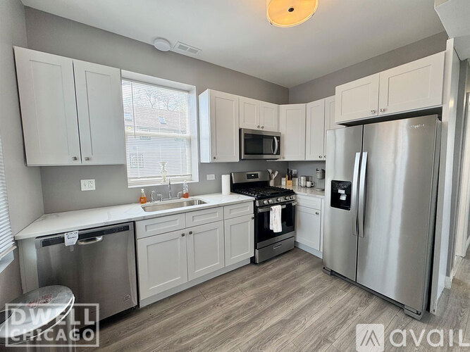 A kitchen with white cabinets and a stainless steel refrigerator.