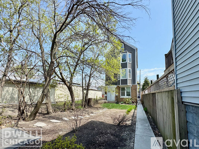 A tree-lined pathway leads to a modern two-story building.