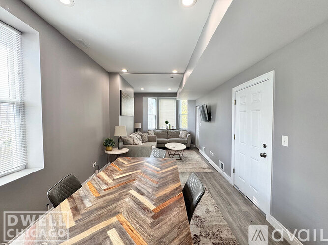 A modern living room with a long wooden table and black chairs.