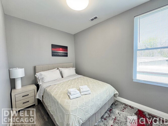 A bedroom with a bed, nightstand, and lamp.