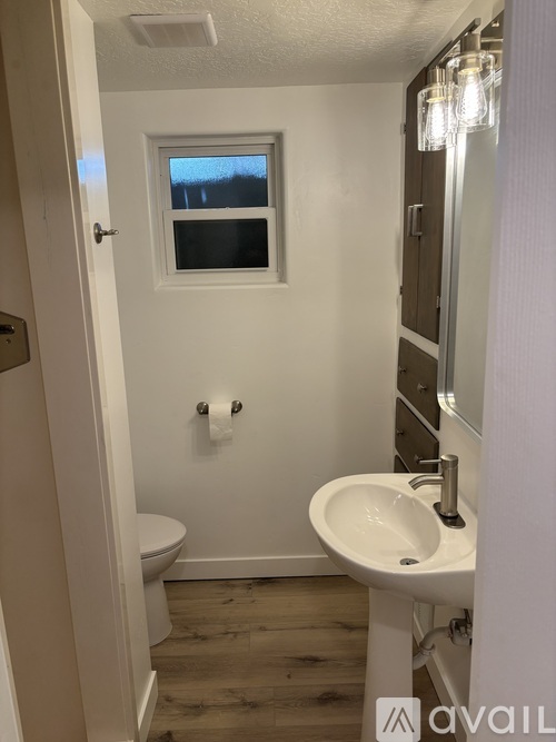 A small white bathroom with a toilet, sink and mirror.