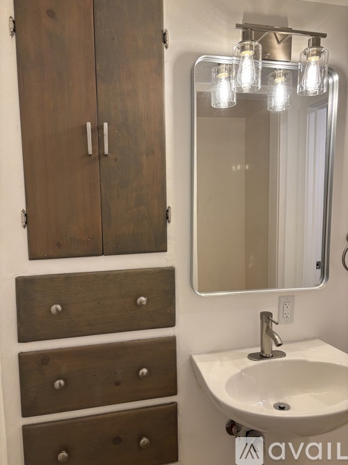 A bathroom with a sink, mirror and wooden cabinets.