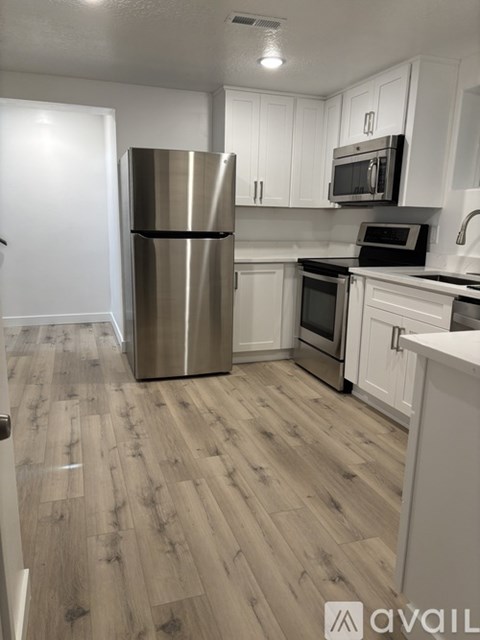 A kitchen with a stainless steel refrigerator and wooden flooring.