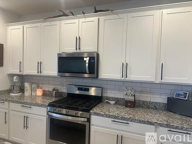 A kitchen with white cabinets and a granite countertop.