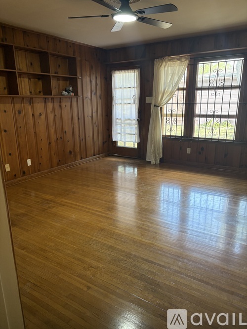 A room with wooden floors and a window with white curtains.
