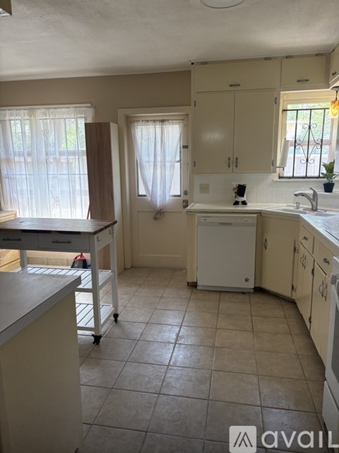 A kitchen with white cabinets and a tiled floor.