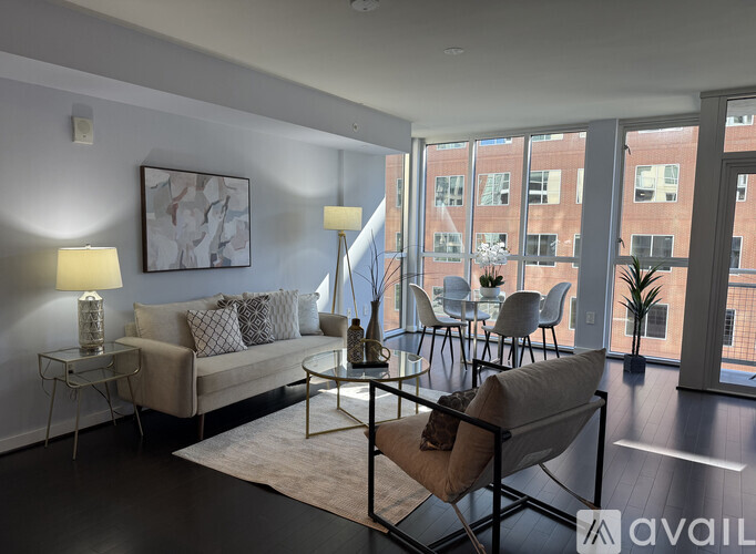 A living room with a couch, chairs, and a table with a lamp on it.