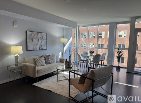 A living room with a couch, chairs, and a table with a lamp on it.