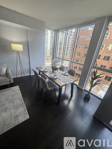 A living room with a grey sofa, a wooden table, and a large window overlooking a cityscape.