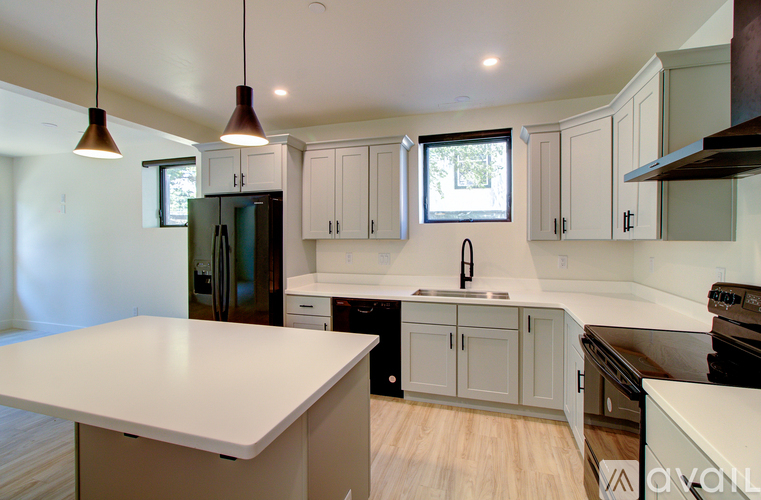 A kitchen with white countertops and a window above the sink.