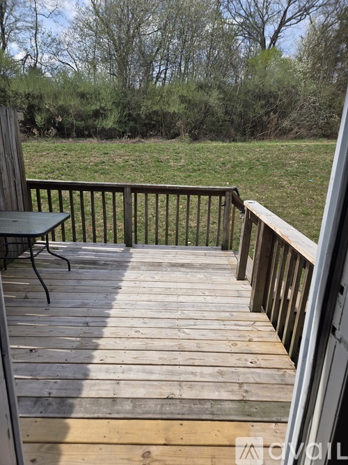 A wooden deck with a table and chairs overlooking a grassy field.