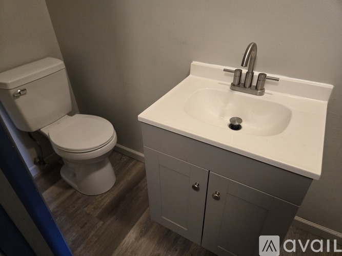 A white sink with a silver faucet and a white toilet in a bathroom.