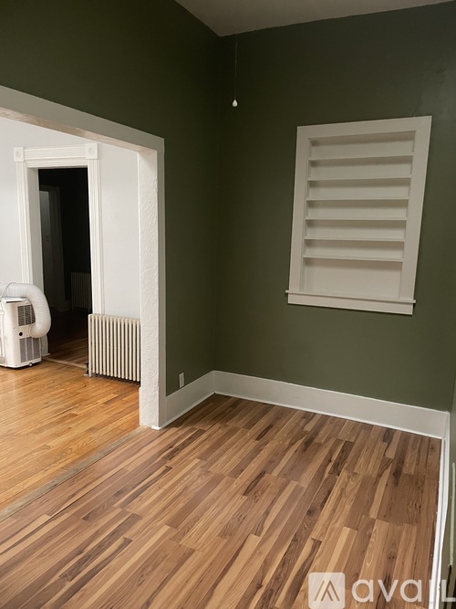 A room with wooden floors and a window with white shutters.