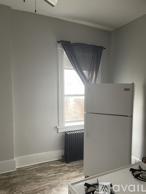 A kitchen with a white fridge and a window with curtains.