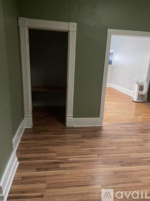 A room with a white doorway and wooden flooring.