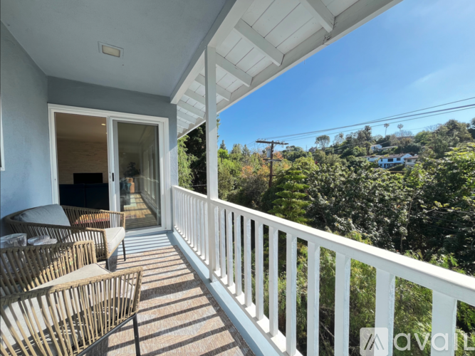 A balcony with white railings and a view of trees and houses in the distance.