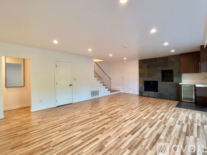 A spacious room with wooden flooring and a staircase.