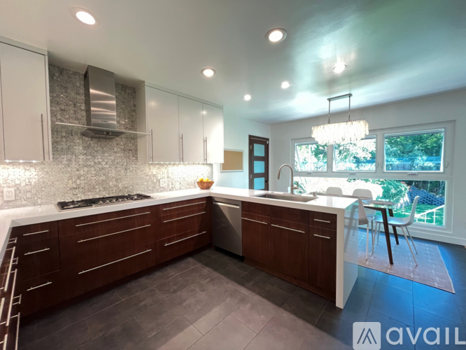 A modern kitchen with dark wood cabinets and a stone backsplash.