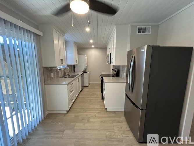 A kitchen with a black refrigerator and white cabinets.