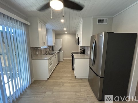 A kitchen with a black refrigerator and white cabinets.