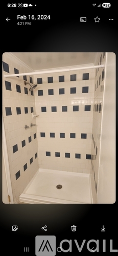 A shower with a white tiled wall and floor.