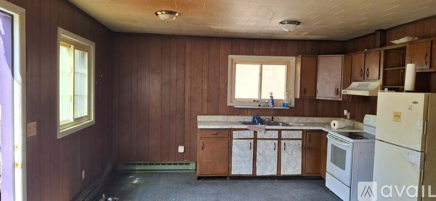 A kitchen with wooden walls and a white fridge.