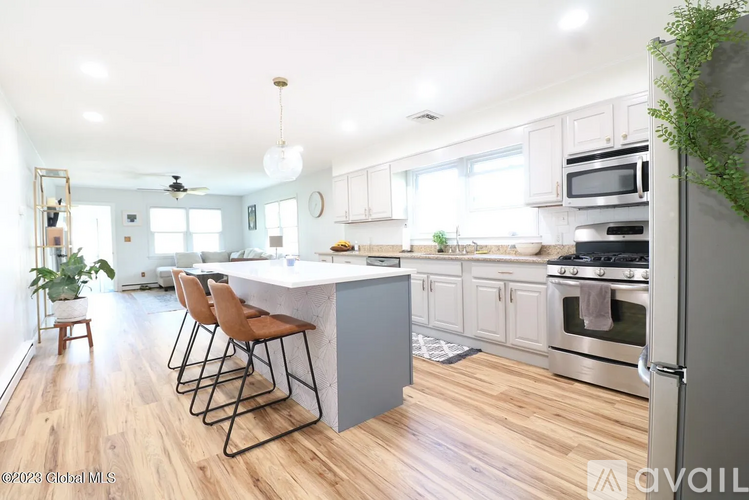 A kitchen with a white island and wooden floors.