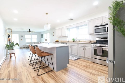 A kitchen with a white island and wooden floors.