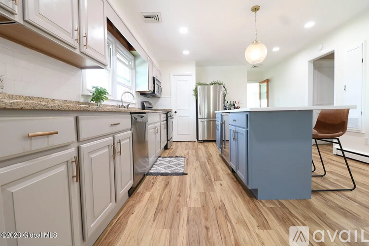 A kitchen with wooden floors and a blue island.