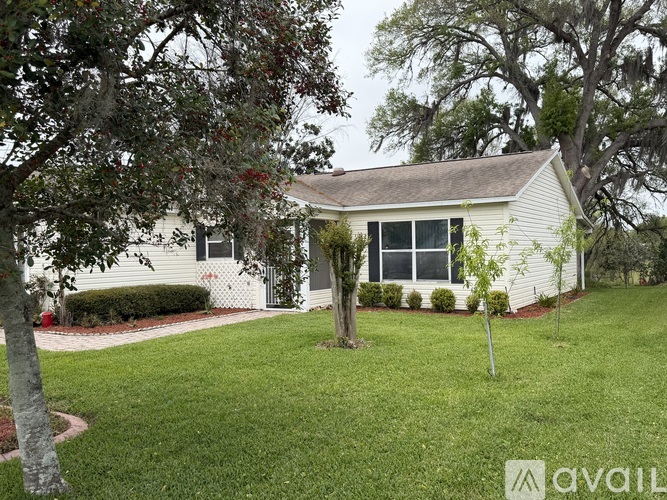 A white house with a green lawn and trees in front.