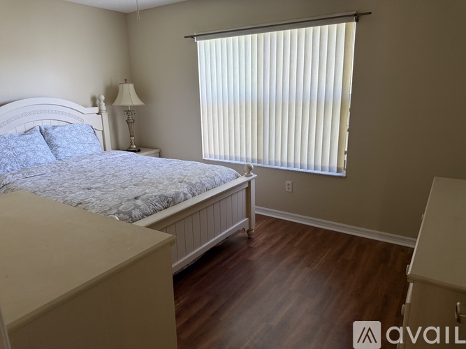 A bedroom with a bed, nightstand, and window with blinds.