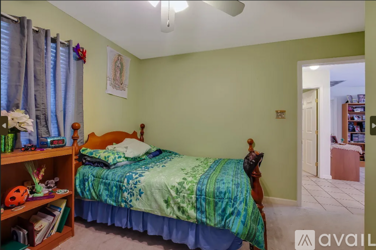 A bedroom with a bed, a dresser, and a window with curtains.